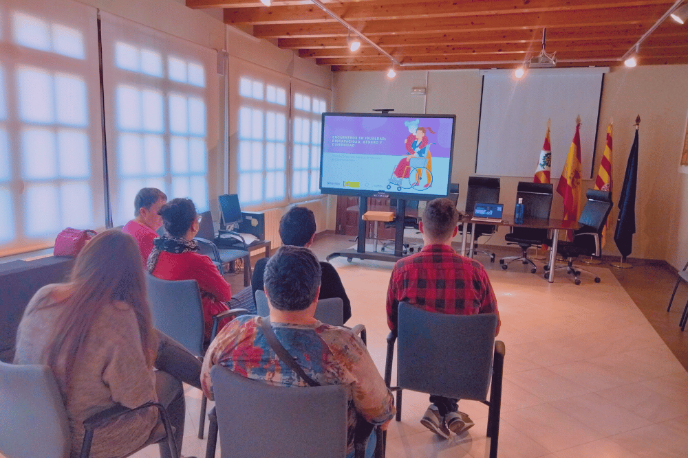 Personas asistiendo a una charla sobre igualdad impartida por Amanixer en una sala del Ayuntamiento de Belchite