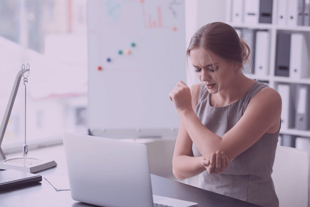 Mujer tocándose el codo con cara de dolor